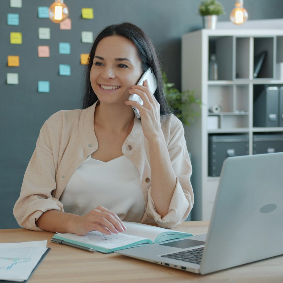 Woman on phone working on laptop